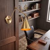 Brass swing arm sconce with a cone shade in a panelled study