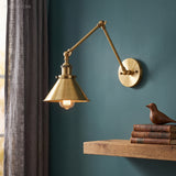 Brass swing arm sconce with a cone shade on a deep teal wall