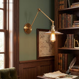 Brass sconce with a flat disc shade above a study writing desk