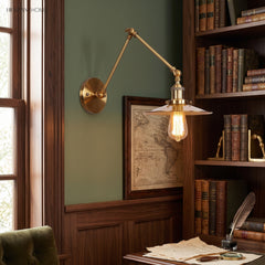 Brass sconce with a flat disc shade above a study writing desk