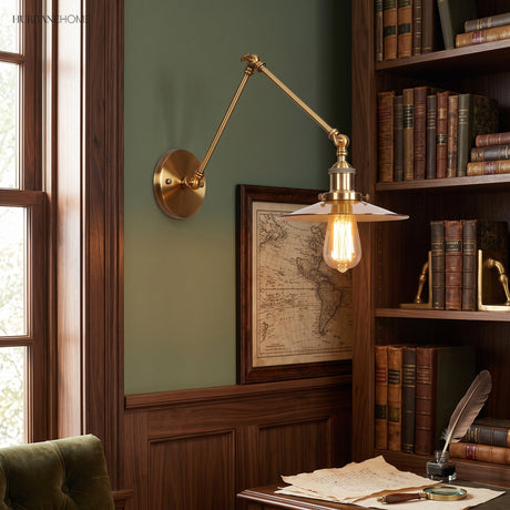 Brass sconce with a flat disc shade above a study writing desk