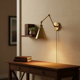 Brass sconce with a deep horn shade angled down on white