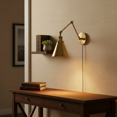 Brass sconce with a deep horn shade angled down on white