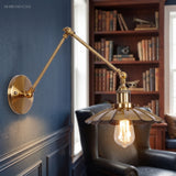 Brass sconce with a scalloped shade lit beside a bright window