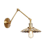 Brass sconce with a scalloped shade and a lit filament bulb
