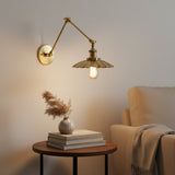 Brass sconce with a scalloped shade lit from below on white