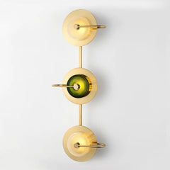 Three light brass sconce with green glass discs running down a white wall