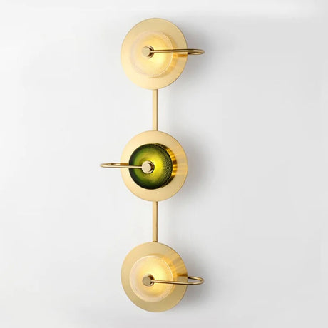 Three light brass sconce with green glass discs running down a white wall