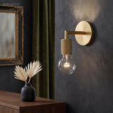 Bare bulb sconce on a dark wall beside a gilt framed mirror