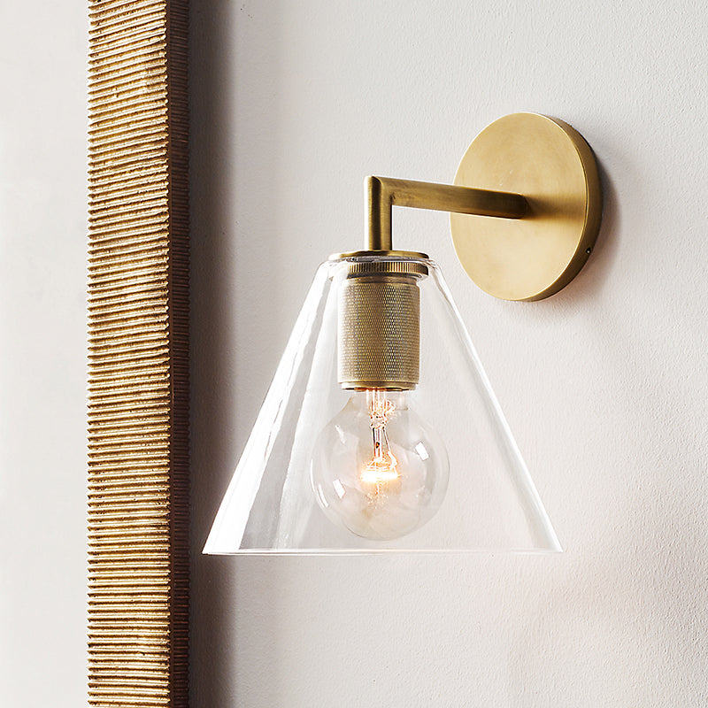 Cone shade sconce on a white wall beside a woven cane panel