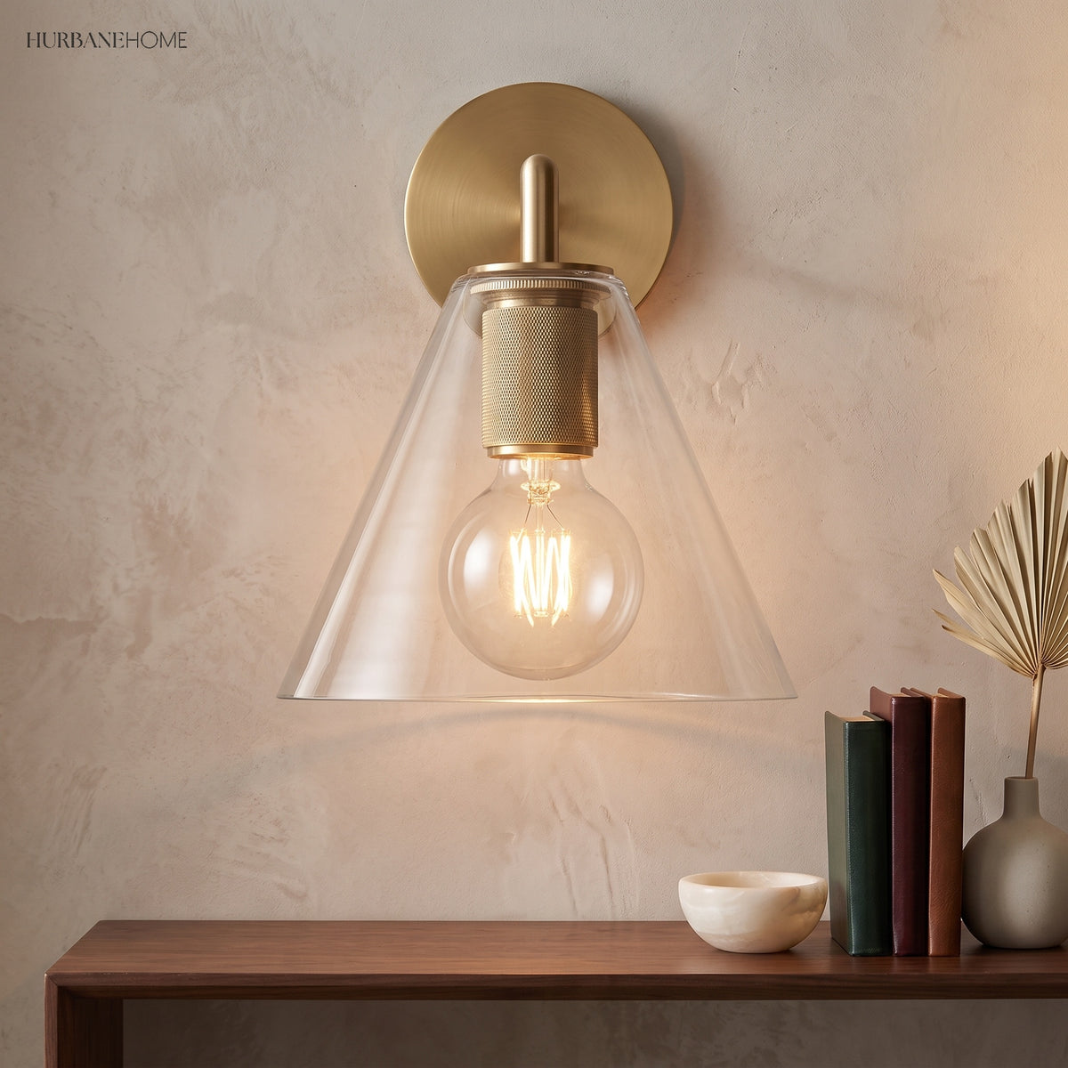 Cone shade sconce lit above a wood console stacked with books