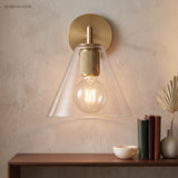 Cone shade sconce lit above a wood console stacked with books