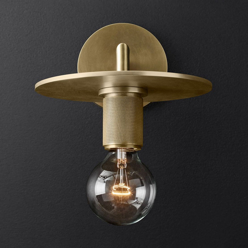 Metal disc shade sconce lit warm against a charcoal background