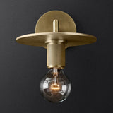 Metal disc shade sconce lit warm against a charcoal background