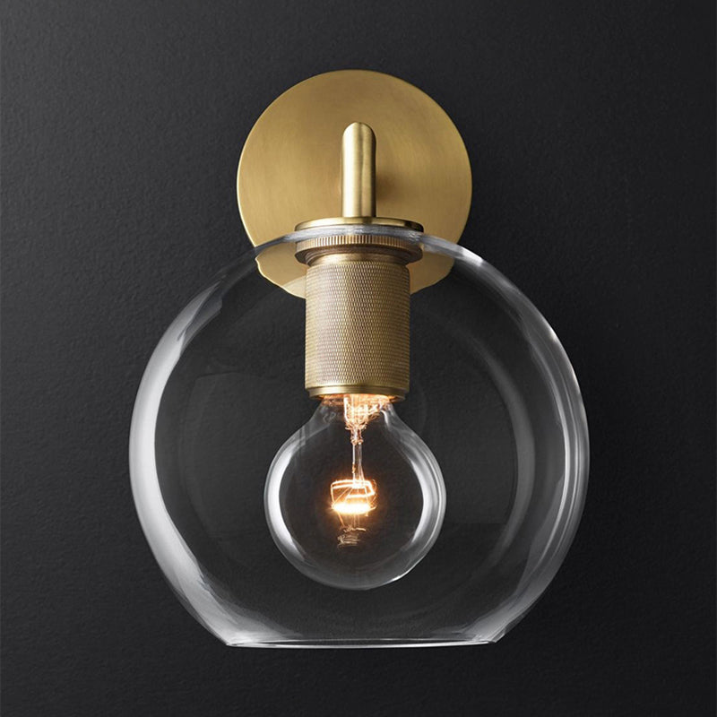 Glass globe shade sconce lit warm against a charcoal background