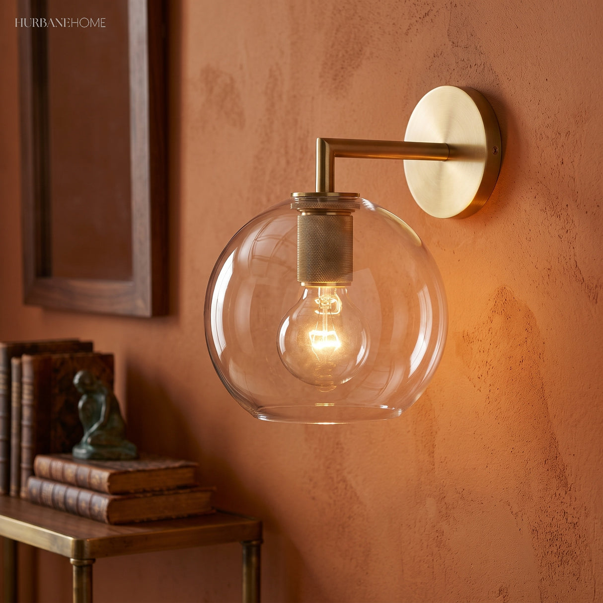 Glass globe shade sconce lit warm on a terracotta colored wall