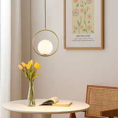 Gold round frame glass globe pendant over a dining table with yellow tulips