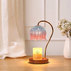 Candle warmer lamp with a pink and blue flower glass shade above a lit candle jar