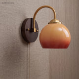 Caramel gradient glass sconce with plug-in cord against a woven wall