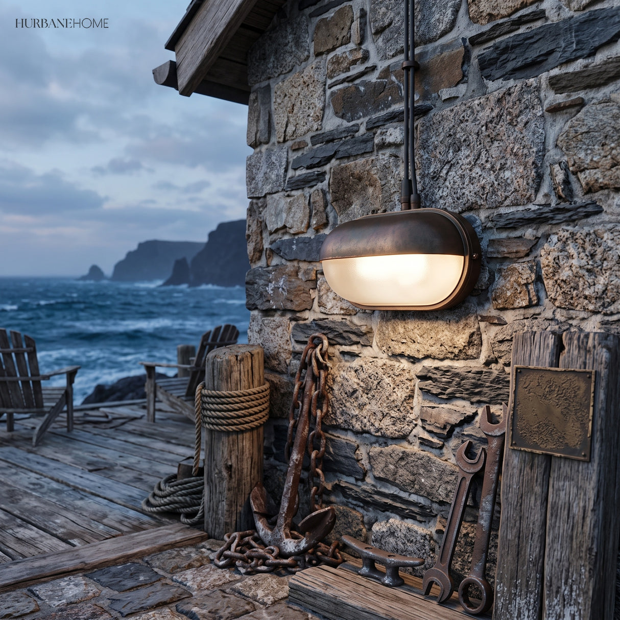 Bulkhead wall lamp lit on a stone wall above a harbour at dusk with chain