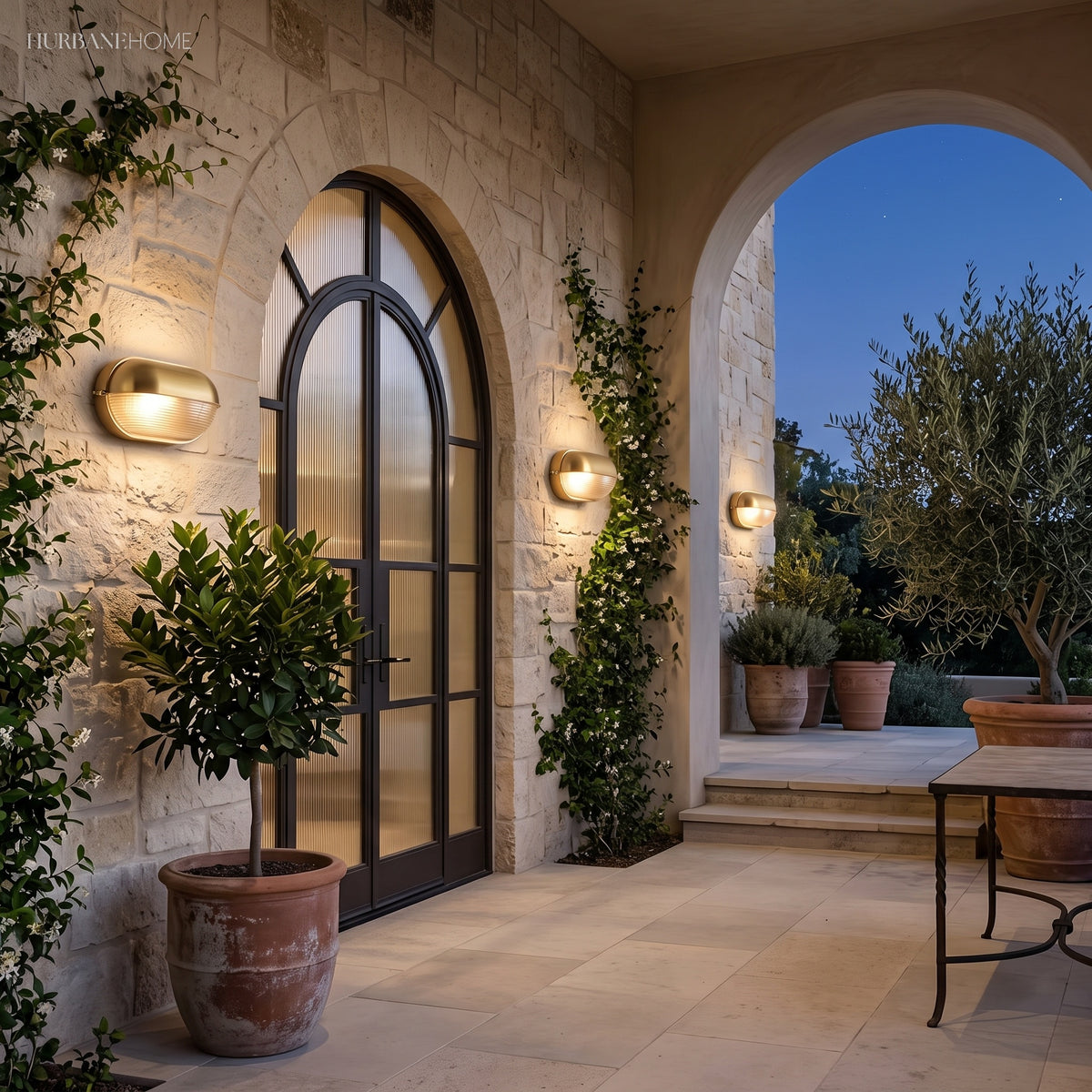 Bulkhead lamps flanking an arched black door on a stone garden terrace