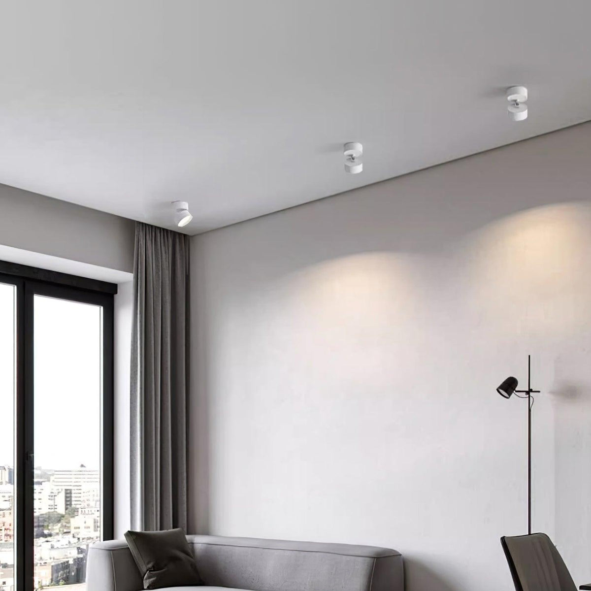 Ceiling spot lights in a plain apartment room with a floor lamp and city window