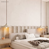 Two cement flower pendant lights flanking a bed in a warm bedroom