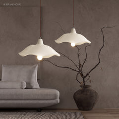 Two cement flower pendant lights above a grey sofa with bare branches