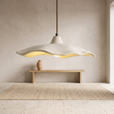 Off-white wavy cement flower pendant light hanging above a wooden bench