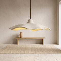 Off-white wavy cement flower pendant light hanging above a wooden bench