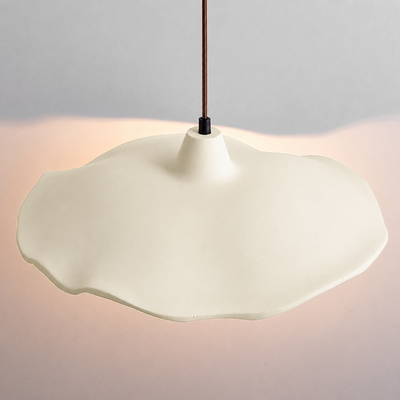 Cement flower pendant light casting warm light on a raw stone wall