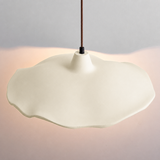 Cement flower pendant light casting warm light on a raw stone wall