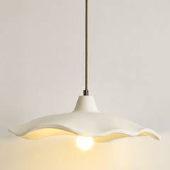 Studio shot of a lit cement flower pendant light with a warm bulb glow