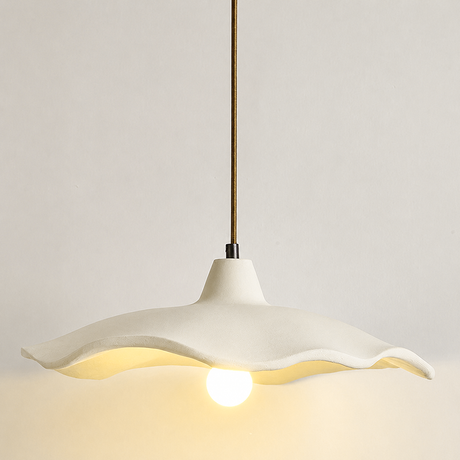 Studio shot of a lit cement flower pendant light with a warm bulb glow