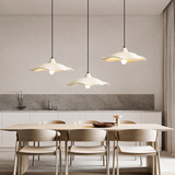 Off-white cement pendant light lit above a dark timber tea setting