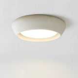 Minimalist cement dome flush mount ceiling light shown from a front three quarter angle