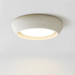 Minimalist cement dome flush mount ceiling light shown from a front three quarter angle