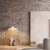 Single cement pendant light glowing against a rough textured stone wall