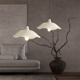 Three-light linear cement pendant fixture over a dining table by a window
