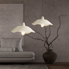 Three-light linear cement pendant fixture over a dining table by a window