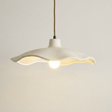Underside of the off-white cement petal shade around an exposed bulb
