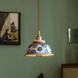 Blue daisy ceramic pendant lit against a deep green wall