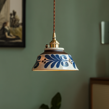 Blue floral ceramic pendant lit warm against a green wall
