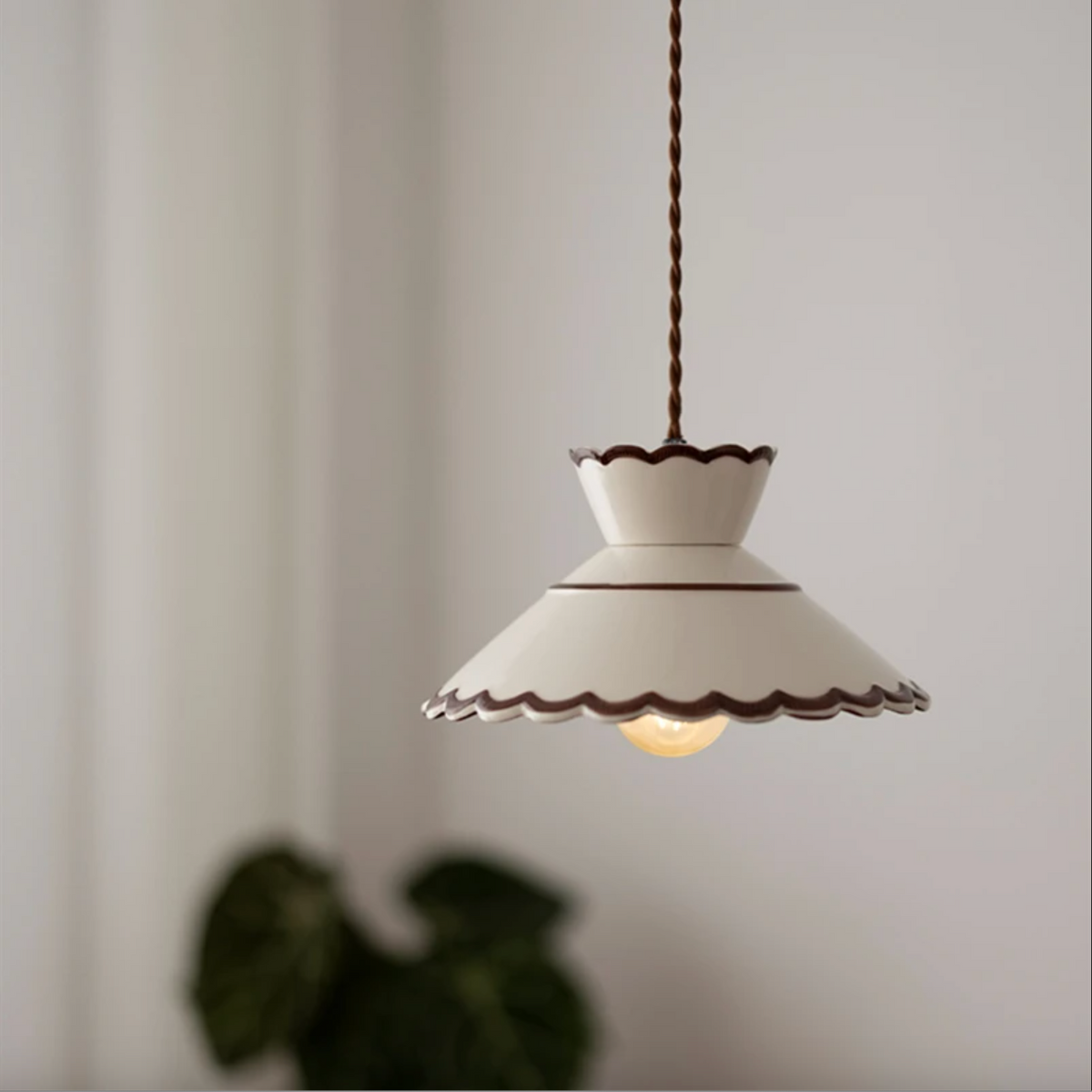 Ivory scalloped ceramic pendant lit in a pale room