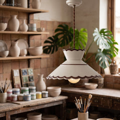 Ivory scalloped ceramic pendant lit above a potters workbench
