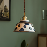 Blue spotted ceramic pendant lit above a green wall and frame