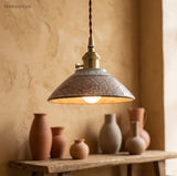 Textured terracotta ceramic pendant lit above a row of vases