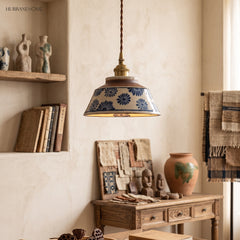 Blue daisy ceramic pendant lit above a workshop table