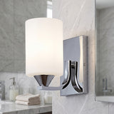Chrome wall sconce with a white glass shade beside a marble bathroom mirror