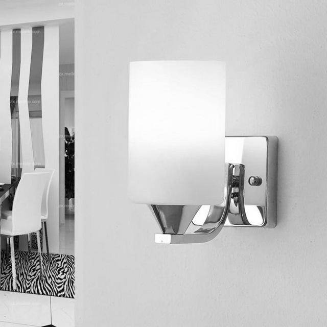 Chrome sconce lit on a mirrored wall panel in a modern interior